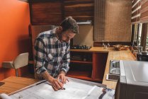 From above side view of male architect drawing blueprint of building while working on project at home — Stock Photo