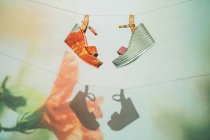 Sandalias de moda colgadas en cuerda contra pared con proyección de flor en verano - foto de stock
