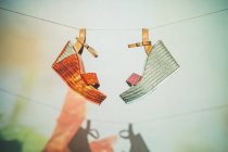 Модні босоніжки, що звисають на мотузці проти стіни з проекцією квітки влітку — стокове фото