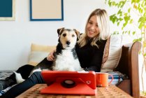 Freundliche Hündin interagiert mit aufmerksamem reinrassigen Hund gegen Tablet mit schwarzem Bildschirm auf dem heimischen Tisch — Stockfoto