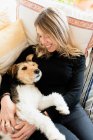 Dall'alto della candida femmina che abbraccia simpatico cane di razza mentre riposa su un letto morbido con cuscini a casa — Foto stock