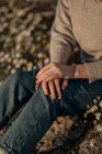 Viajante feminino irreconhecível cultivado em desgaste casual sentado sozinho no prado florido contra o campo arado borrado enquanto relaxa no campo no dia da primavera — Fotografia de Stock