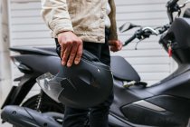 Side view of crop anonymous male motorcyclist with protective helmet standing against modern motorbike in town — Stock Photo