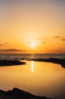 Vista panorâmica do céu de pôr-do-sol laranja vívido sobre a água do mar calma à noite — Fotografia de Stock