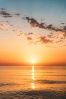 Мальовничий вид на яскраве оранжеве небо заходу сонця над спокійною морською водою ввечері — стокове фото