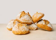 Вкусный хлеб круглой формы с мукой на золотой поверхности в пекарне на белом фоне — стоковое фото