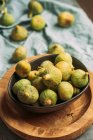 Fresh and ripe sweet green figs, in a black bowl on the wood plate served on the blue tablecloth table, Seasonal organic fruit. Also known as ripe white figs — Stock Photo