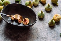 Fatias de figo verde em tigela preta moderna na mesa com textura grunge. comida conceito mínimo. Também conhecido como figos brancos maduros — Fotografia de Stock