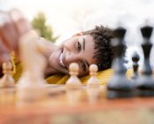 Dal basso di una donna afroamericana ottimista seduta al tavolo del parco a giocare a scacchi guardando la macchina fotografica — Foto stock