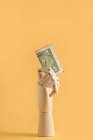 Nota de dólar em mão de madeira colocada sobre fundo laranja em estúdio mostrando conceito financeiro — Fotografia de Stock