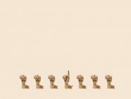 Dall'alto del modello di mani di legno con pugni serrati e uno con indice rivolto verso l'alto su sfondo beige — Foto stock