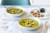 Dall'alto di zuppa di crema di zucchine buonissima con crostini in ciotole serviti sul tavolo a casa — Foto stock