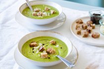 Dall'alto di zuppa di crema di zucchine buonissima con crostini in ciotole serviti sul tavolo a casa — Foto stock