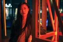 Ritratto di ragazza asiatica in piedi vicino alla luce al neon di notte sulla strada — Foto stock