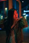 Porträt eines asiatischen Mädchens, das nachts in der Nähe von Neonlicht auf der Straße steht — Stockfoto