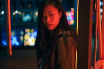 Portrait de fille asiatique debout près de la lumière au néon la nuit dans la rue — Photo de stock