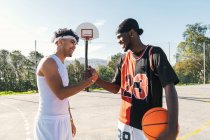 Vista lateral de jogadores de streetball masculino afro-americanos apertando as mãos enquanto estão de pé no playground de basquete e olhando um para o outro — Fotografia de Stock