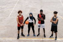 Сверху определились различные игроки команды по стритболу, стоящие вместе на баскетбольной площадке и смотрящие в камеру — стоковое фото