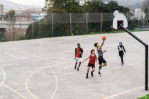 Angolo alto di amici multietnici che giocano a basket su un campo sportivo in estate — Foto stock