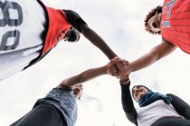 From below of multiracial team of streetball players stacking hands together before basketball match — Stock Photo