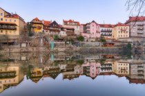 Pintoresca vista de viejos edificios residenciales en mal estado que reflejan en aguas tranquilas del río - foto de stock