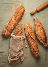 Top vista composição de deliciosos pão crocante artesanal sourdough pães embalados em sacos de serapilheira no fundo verde — Fotografia de Stock