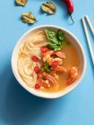 Tom-Yum-Suppe in Schüssel mit Stäbchen auf blauem Hintergrund — Stockfoto