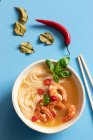 Tom-Yum-Suppe in Schüssel mit Stäbchen auf blauem Hintergrund — Stockfoto