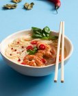 Tom yum soup in bowl with chopsticks on blue background — Stock Photo