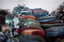 Muchas motocicletas oxidadas dañadas anticuadas colocadas en filas en el taller de servicio de reparación - foto de stock