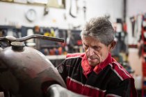 Senior meccanico di sesso maschile riparazione vecchio arrugginito smontato moto mentre si lavora in officina professionale — Foto stock