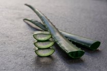 Piece and leaf of green aloe vera placed on gray background in studio — Stock Photo