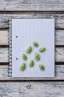 From above of raw green beans and pen placed on notepad on wooden table — Stock Photo