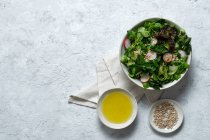 Вид зверху на свіжий здоровий овочевий салат у мисці, який подається на столі з оливковою олією та насінням соняшнику — стокове фото