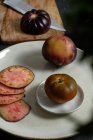 Dall'alto pomodori neri interi e affettati freschi sul tavolo durante preparazione di pasto sana — Foto stock