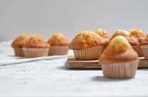 Deliziosi muffin dolci fatti in casa appena sfornati in bicchieri di carta disposti sul tavolo — Foto stock