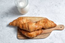 De cima deliciosos croissants e garrafa de leite colocado na mesa para o café da manhã na cozinha — Fotografia de Stock
