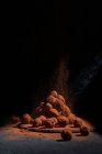 Altura de deliciosas trufas de chocolate em forma de bolas empilhadas na mesa em fundo escuro no estúdio — Fotografia de Stock