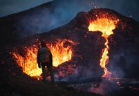 Homem explorador observando as faíscas magma fora do vulcão Fagradalsfjall na Islândia entre nuvens de fumaça — Fotografia de Stock