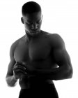 Schwarz-Weiß eines emotionslosen, muskulösen jungen schwarzen Mannes mit gefalteten Händen und geschlossenen Augen im Studio auf weißem Hintergrund — Stockfoto