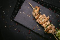 From above of appetizing freshly cooked meat on skewer served on tray on black table — Stock Photo