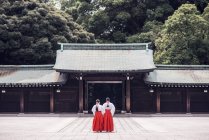 Обратный вид на неузнаваемых людей в традиционном кимоно, стоящих за пределами древнего храма Мэйдзи, расположенного в горах в Сибуя в Токио, Япония — стоковое фото