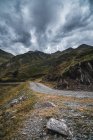 Malerische Landschaft der leeren Route mit trockenem und grünem Gras in bergigem Gelände des Aran-Tals in Spanien unter grauem wolkenverhangenem Himmel — Stockfoto