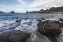 Vista panorâmica de formações rochosas na praia de Gueirua perto do mar calmo sob o céu azul nas Astúrias — Fotografia de Stock