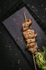 Сверху аппетитное свежеприготовленное мясо на шампуре подается на подносе на черном столе — стоковое фото