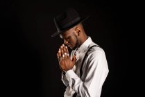 Vue latérale de jeune homme afro-américain non rasé en chemise blanche et anneaux sur les doigts avec des mains de prière — Photo de stock