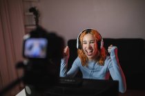 Усміхнена геймерка в навушниках записує відео на професійній камері для блогу соціальних мереж — стокове фото