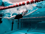 Femme rampant dans une piscine se préparant pour une compétition — Photo de stock