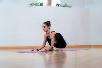 Босонога жінка в спортивному одязі розтягується під час практики йоги — стокове фото