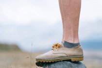 Vista lateral del excursionista femenino en botas de pie sobre roca en la naturaleza durante el trekking en verano - foto de stock